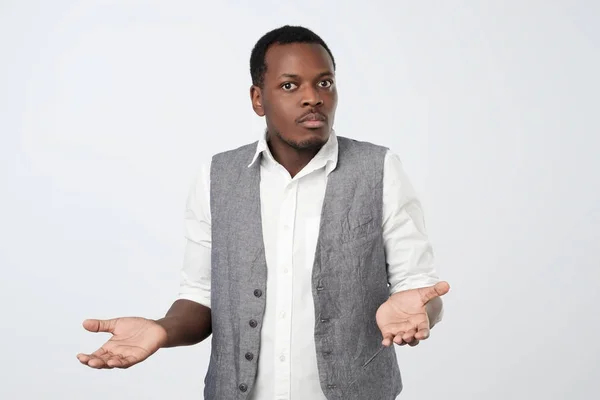 Young african man in blue shirt being at a loss, showing helpless gesture with arm and hand — Stock Photo, Image