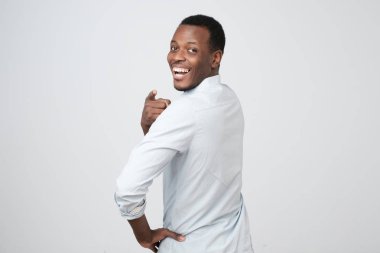 Arkadan kamera geri dönüş ve beyaz arka plan üzerinde izole kamera, parmak ile işaret mutlu gülümseme ile seyir çekici Afrikalı adamın görünüşü. O sendin, gördüm,