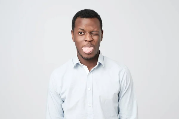 Mladý vtipné afro americký muž dělá grimasy, ukazuje jazyk jako hádky s přítelkyní. — Stock fotografie