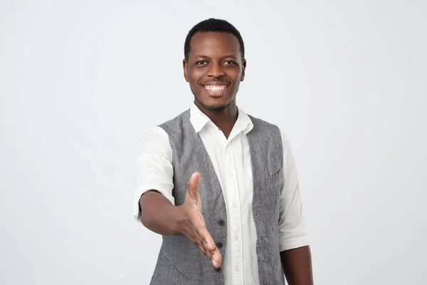 Красивый молодой африканский мужчина в белой рубашке и жилете пожимает руку для рукопожатия. — стоковое фото