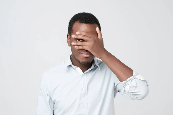 Atractivo joven africano agradable cerrando los ojos con la palma y espiando tratando —  Fotos de Stock