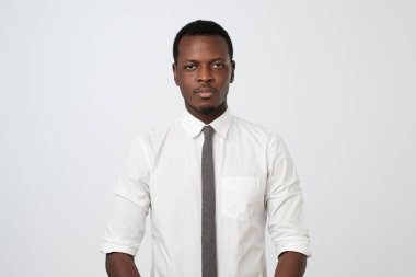 Afro Amerikan zenci beyaz stüdyo duvara poz kameraya bakarak ciddi ifade ile düşünme. Beyaz gömlek ve kravat iş hakkında düşünme mezar işadamı