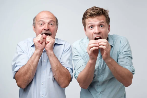 Двое ошеломленных мужчин реагируют на внезапные новости, держат рот открытым, смотрят в камеру — стоковое фото