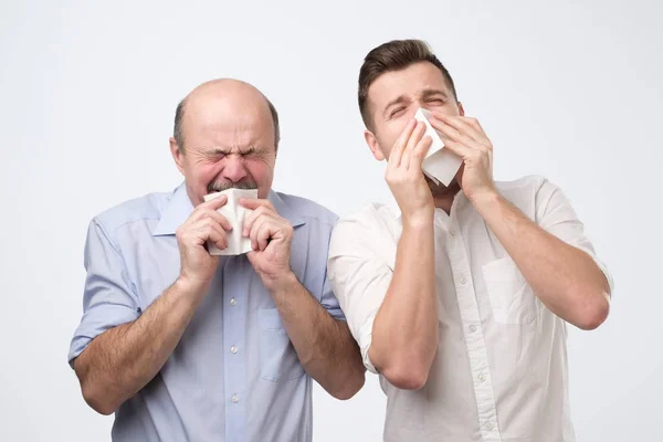 Padre e hijo estornudan estando enfermos —  Fotos de Stock