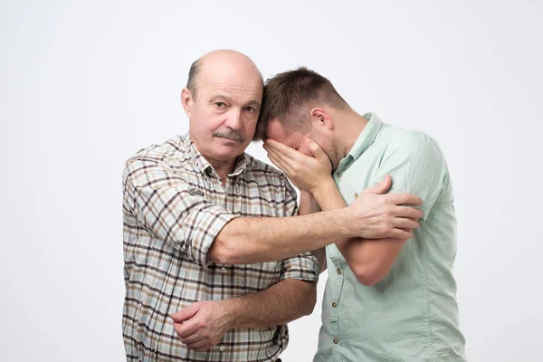 Зрілий син плаче на плечі батька і відчуває засмучені причини своєї помилки . — стокове фото