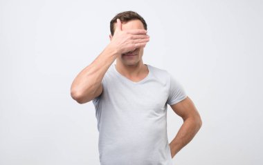 Tanınmayan adam gözlerini utanıyorum, hissederken kapsayan ile boş stüdyo duvar karşı ayakta