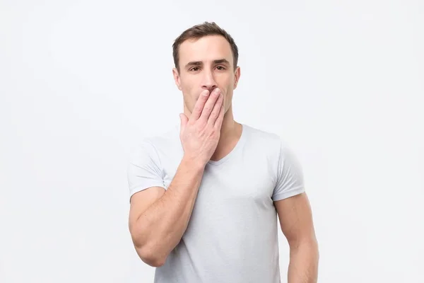 Geschokt Italiaanse jongeman in wit t-shirt die betrekking hebben op mond met handen en camera te kijken — Stockfoto