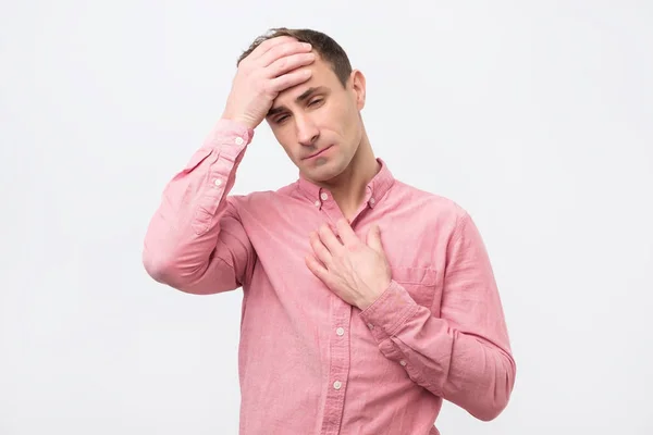 Молодой человек в розовой рубашке страдает от гриппа и лихорадки . — стоковое фото