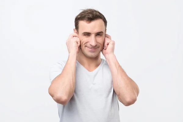 Cheerful italian man plugging ears with fingers and winking. — Stock Photo, Image