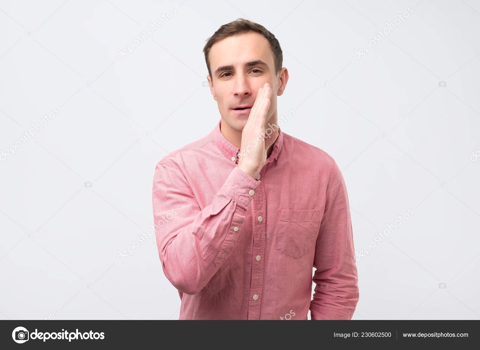 Just do not tell anyone concept. Young man in pink shirt whispering trade secrets Stock Photo by