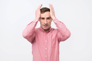 Ellerini başının üstüne beyaz arka plan üzerinde tutarak histerik ifade ile olgun adam.