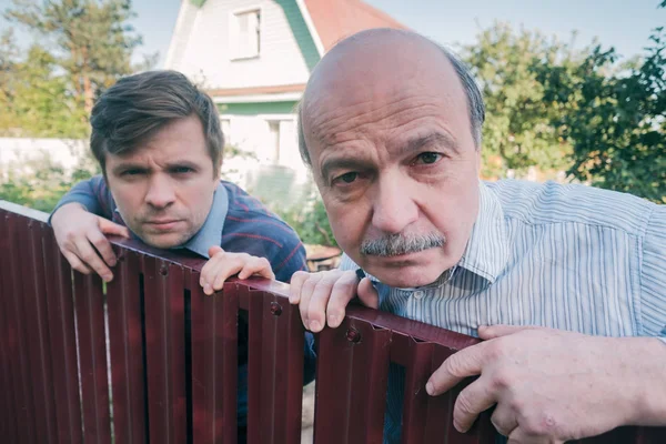 Two caucasian men carefully watching over the fence. — Stock Photo, Image