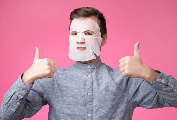 man in a cosmetic mask for skin care showing thumb up