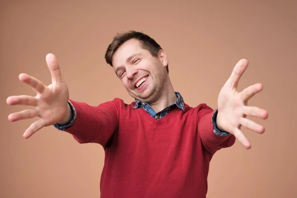 Welcome, nice to see you. Man in red sweater looking at camera with raised arms and happiness. — Stock Photo, Image