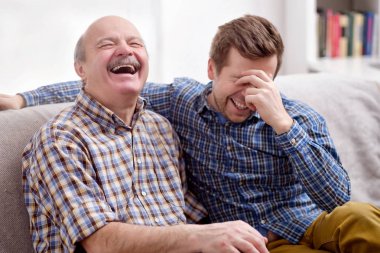 İki adam baba ve oğul evde oturma odasında kanepede oturan ve komik olaylar geçmişten hatırlıyorum. Onlar gül gülen ben olacağım. İyi Aile ilişkileri