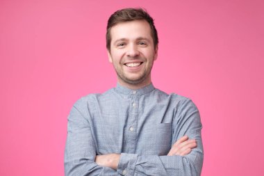 Çekici yakışıklı gülümseyen pozitif Beyaz tişörtlü adam mavi pembe bir arka plan üzerinde. Stüdyo çekimi