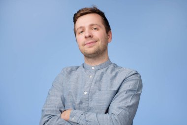 Kendine güvenen genç yakışıklı adam mavi gömlekli geçti ve mavi arka plan karşı dururken gülümseyen silah tutmak