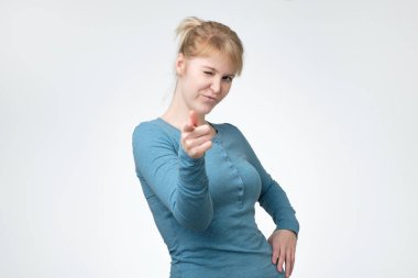 Mavi longsleeve sana beyaz bir arka plan üzerinde işaret içinde gülümseyen kadın