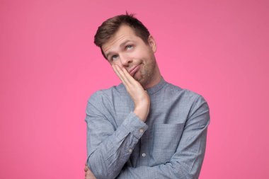 Çok şirin erkek kalp erime. Avuç içi ellerde yaslanmış ve pembe bir arka plan üzerinde sevgi ile gülümseyen yanaklarda mutlu komik adam