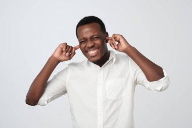 Parmak ile kulakları tıkalı ve göz kırpıyor Beyaz tişörtlü neşeli Afrika adam.