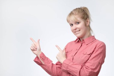 Genel olarak kameraya gülümseyen, uzakta parmakları işaret, ilginç bir şey gösterilen sarışın genç kadın