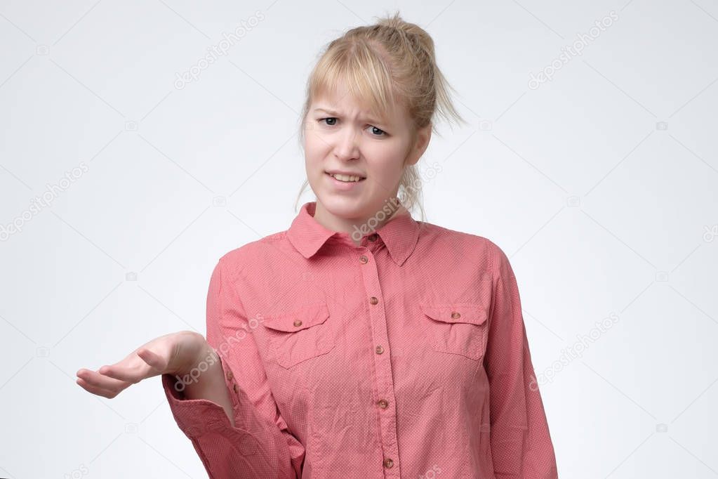 Woman with blonde hair looking in confusion, shrugs shoulders as do not know answer, being clueless