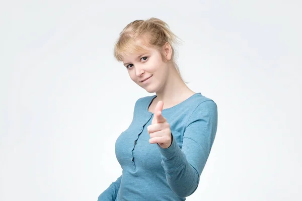 Mulher sorridente de manga comprida azul apontando para você — Fotografia de Stock