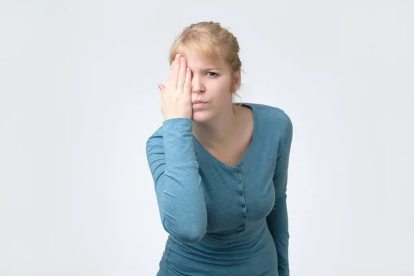 Mujer rubia mirando a la cámara, cubriéndose el ojo con una mano . —  Fotos de Stock