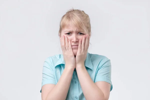 Schattige blonde vrouw gelet op zoek moe die haar hand op Wang. — Stockfoto