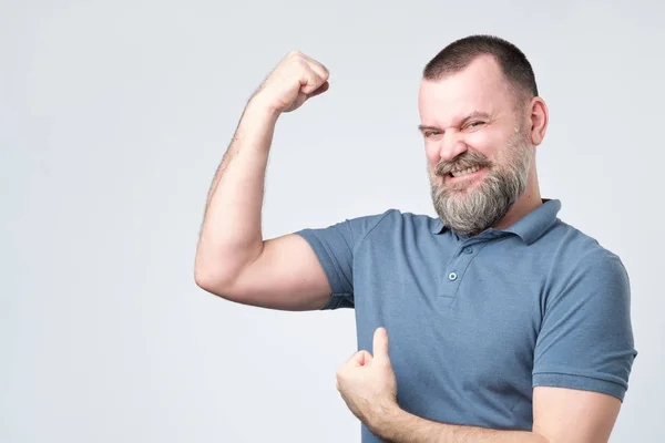 Handsome middle age european bearded man over showing arm muscle — Stock Photo, Image