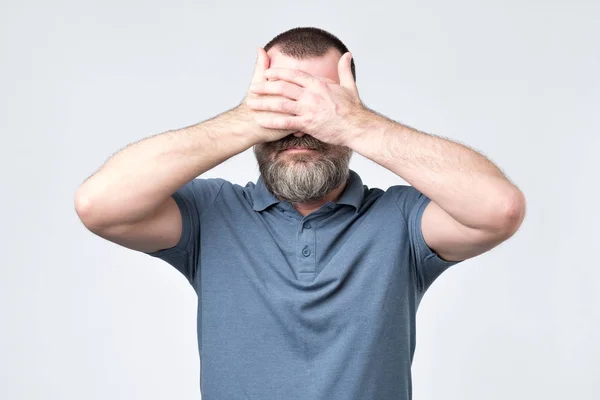 Hombre de camiseta azul cubriéndose la cara con las manos — Foto de Stock