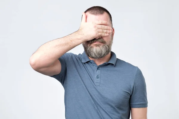Hombre de camiseta azul cubriéndose la cara con las manos — Foto de Stock