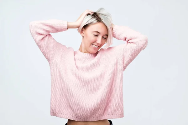 Mujer con el pelo teñido, vestida con suéter rosa, mirando con satisfacción a la cámara, siendo feliz . —  Fotos de Stock