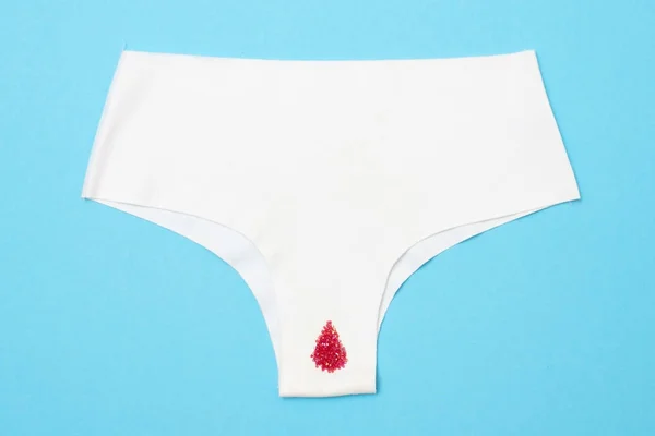 Piros csepp a gyöngyök a nadrág kék háttér. Menstruáció időszak — Stock Fotó