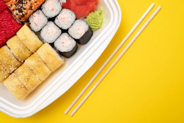 Üstten Görünüm suşi ayarla renkli arka plan üzerinde. Plaka rulo, zencefil ve vasabi ile