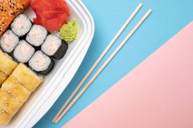 Üstten Görünüm suşi ayarla renkli arka plan üzerinde. Plaka rulo, zencefil ve vasabi ile