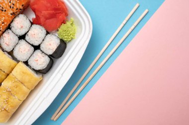Üstten Görünüm suşi ayarla renkli arka plan üzerinde. Plaka rulo, zencefil ve vasabi ile