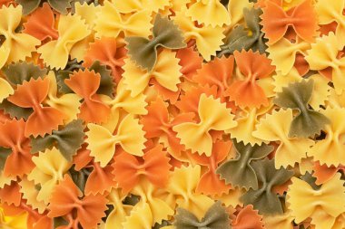 Ham farfalle makarna yığın üst üzerinde izole sarı arka plan görüntüleme