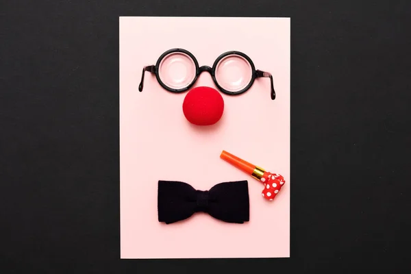 Gafas graciosas, nariz de payaso rojo y corbata se encuentran sobre un fondo de color, como una cara . — Foto de Stock