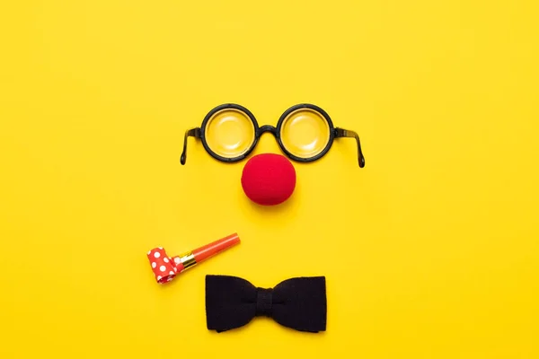 Gafas graciosas, nariz de payaso rojo y corbata se encuentran sobre un fondo de color, como una cara . —  Fotos de Stock