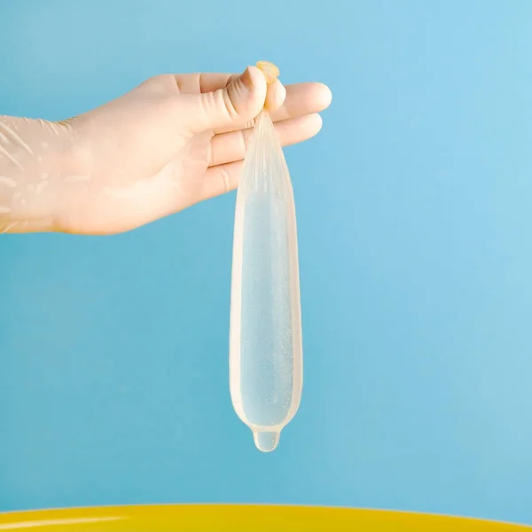 Hand in medical gloves holding condom full of water — Stock Photo, Image