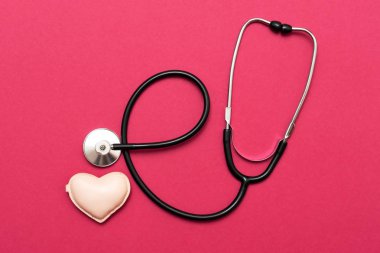 Kalbi steteskop kırmızı arka plan ile. Düz yatıyordu