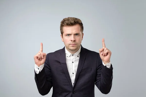 Portrait of a thoughtful european man pointing finger up — Stock Photo, Image