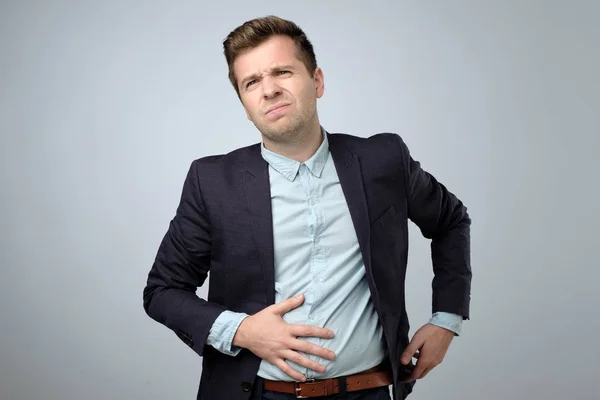 Europejskiego młodego człowieka w garniturze, o ból brzucha. Kolka i wzdęcia — Zdjęcie stockowe
