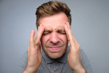 Baş ağrısı acı el ile kafa sıkma mutsuz genç adam üzgün.