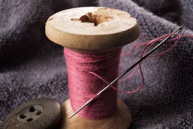 Ahşap makara makro görünümü üzerinde dikiş iğne ve pamuk ipliği.