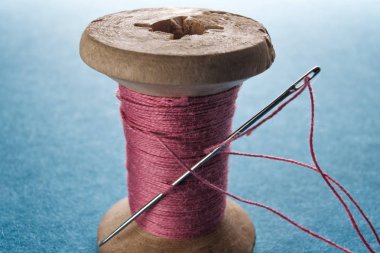 Ahşap makara makro görünümü üzerinde dikiş iğne ve pamuk ipliği.