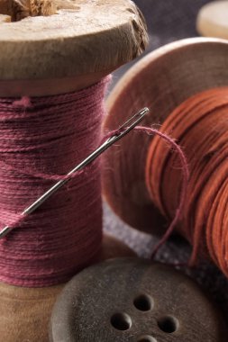Ahşap makara makro görünümü üzerinde dikiş iğne ve pamuk ipliği.