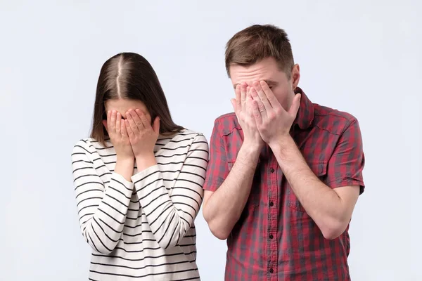 Portrait of a young european couple covering face with hands — Stock Photo, Image