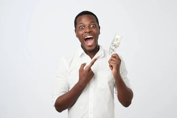 Jeune homme riche afro-américain en chemise tenant cent dollars avec surprise — Photo